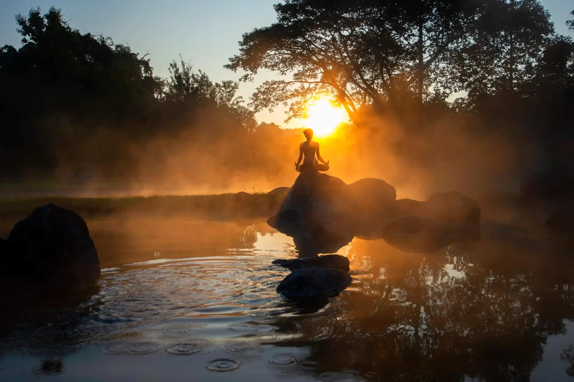A person is sitting on the back of a boat in water.